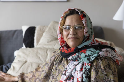 Portrait of smiling mature woman wearing scarf and eyeglasses at home