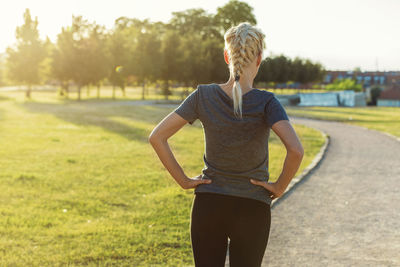 Rear view of woman with braided hair standing on footpath