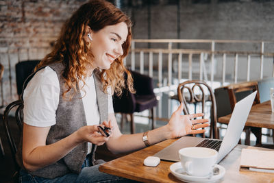 Young woman using mobile phone while sitting on table