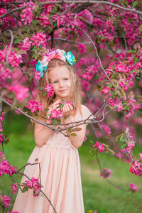 Portrait of girl standing by flowering tree at park