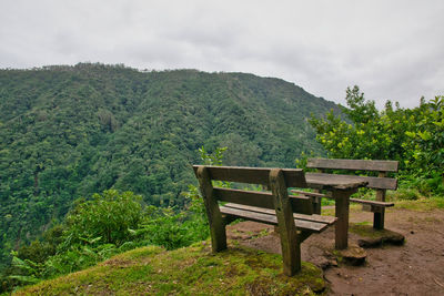 Bench on table by mountains against sky