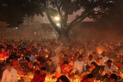 Praying at rakher upobash infront of burning candle and incense