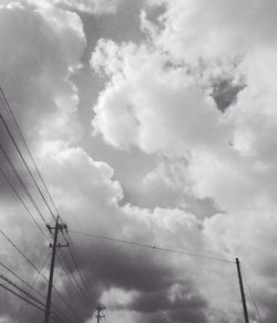 Low angle view of electricity pylon against cloudy sky