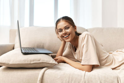 Young woman using laptop while lying on bed at home