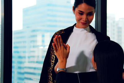 Mid adult woman standing against window