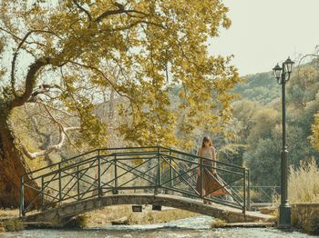 Woman standing by railing against trees