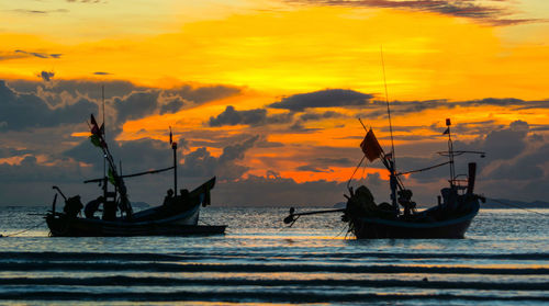 Silhouette boats in sea against sky during sunset