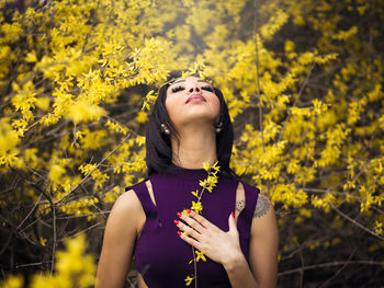 Young woman standing by yellow flowering plants