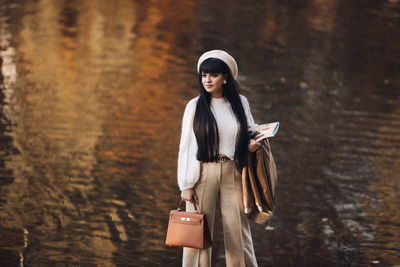 Portrait of young woman standing against wall