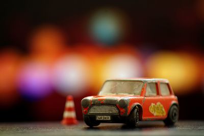 Close-up of toy car and traffic cone on table against defocused background