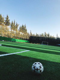 Soccer field by trees against sky