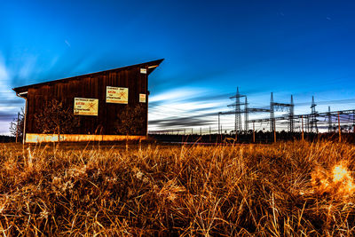 Abandoned building on field against blue sky