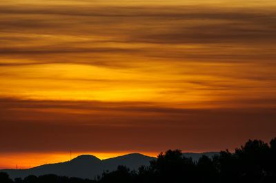 Scenic view of silhouette mountains against orange sky