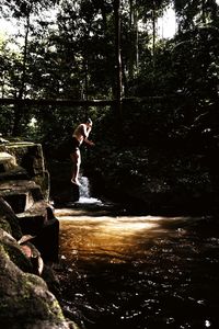 Man standing by waterfall in forest