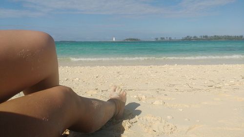 Low section of woman at beach against sky