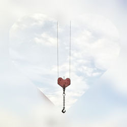 Digital composite image of heart shape hanging against sky