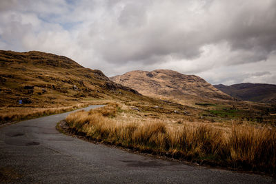 Scenic view of road by mountains against sky