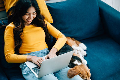 Young woman using laptop while sitting on sofa at home