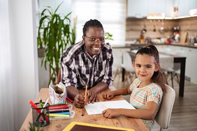 Portrait of young woman using digital tablet while sitting on table