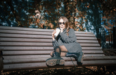 Portrait of woman sitting on bench in park