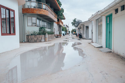 Wet street amidst buildings in city during rainy season