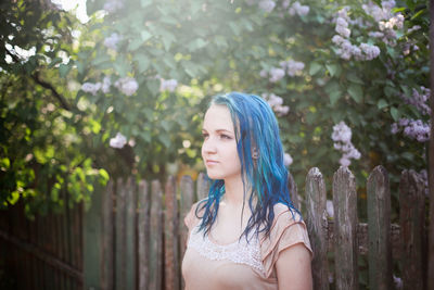 Portrait of beautiful young woman standing against plants