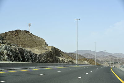 Empty road by mountain against sky