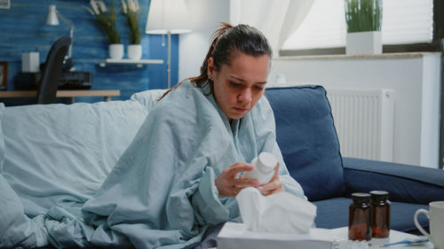 Ill woman sitting on sofa at home