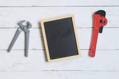 Directly above shot of blackboard with work tools on wooden table