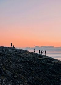 Silhouette people on beach against sky during sunset