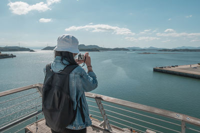 Man photographing on sea against sky