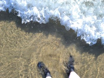 Low section of person standing in sea