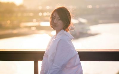 Portrait of smiling woman standing by railing