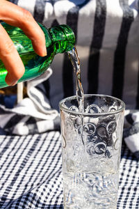 Close-up of hand pouring water in glass on table