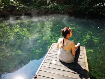 Rear view of woman sitting on lake