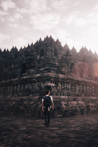 Rear view of man walking against temple