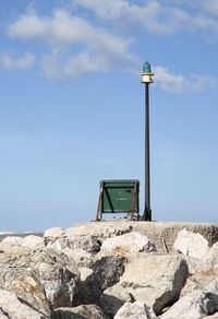 Low angle view of rocks and lamp against sky