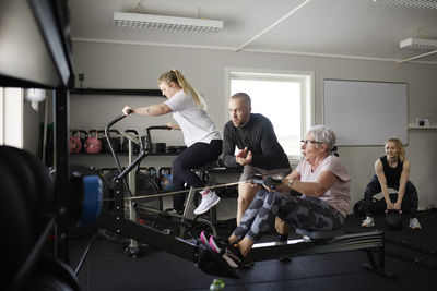 Coach assisting to senior woman exercising in gym