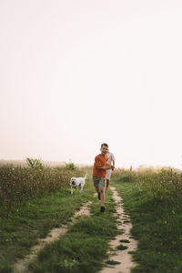 Portrait of a smiling little boy in a orange t-shirt and playing outdoors on the field at sunset