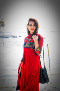 Portrait of beautiful woman standing on shore at beach