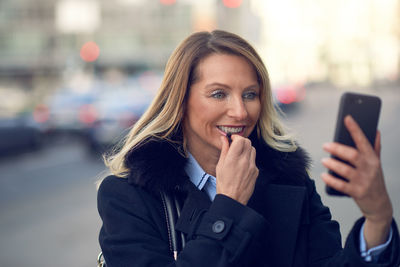 Smiling businesswoman using smart phone in city