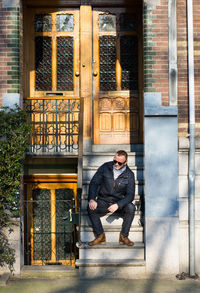 Portrait of young man standing against door of building