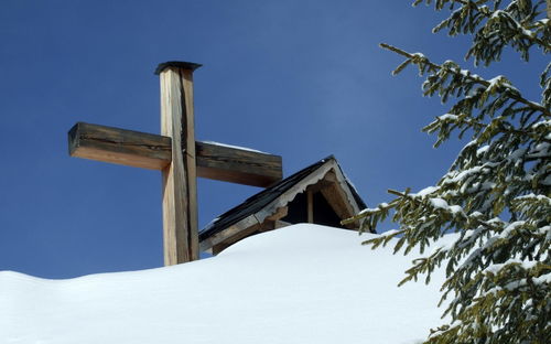 Low angle view of cross against clear sky during winter