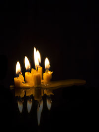 Close-up of burning candle against black background