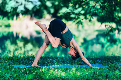 Young woman practicing yoga by the water