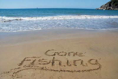 Beach with gone fishing written on sand, boat on the horizon. magnetic island, queensland, australia