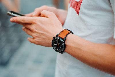Midsection of man holding mobile phone