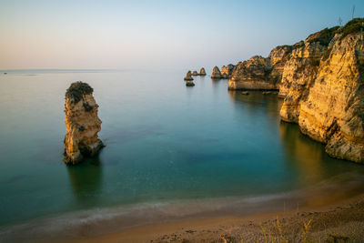 Rock formations on beach against sky