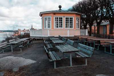 Empty bench and tables against built structure in city