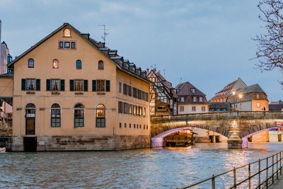 Arch bridge over river against buildings in city